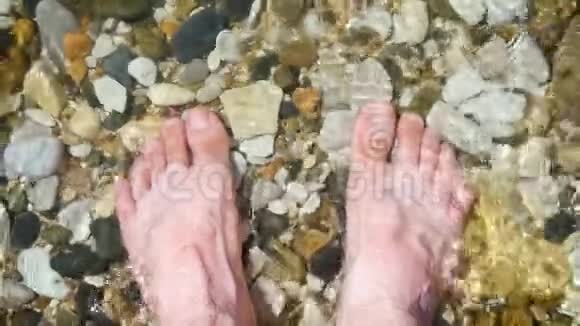 一个赤脚的人站在水中的鹅卵石海岸上冲浪击中了那个人腿娱乐和旅游视频的预览图