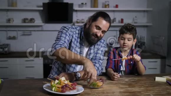 可爱的爸爸和儿子做美味的水果串视频的预览图