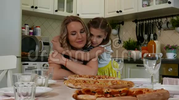 可爱的金发女孩和妈妈坐在厨房的餐桌上视频的预览图