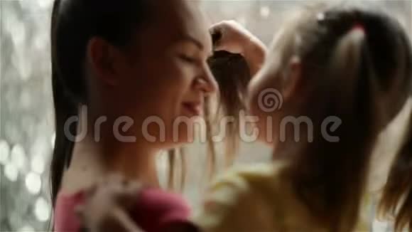 可爱的小女孩正在拥抱和亲吻她美丽的年轻妈妈母亲节快乐瀑布在背景上视频的预览图