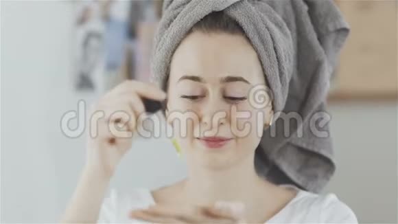 女人头上戴着毛巾脸上涂着油润肤露看着镜头视频的预览图