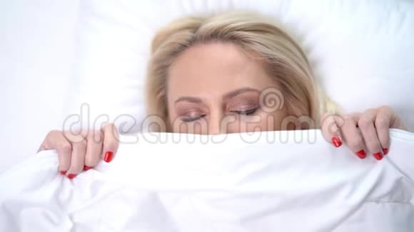 家中睡在白色羽绒被下的成年女性视频的预览图