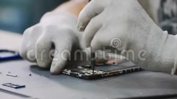 白手套修理工在车间用螺丝刀拆卸智能手机视频的预览图