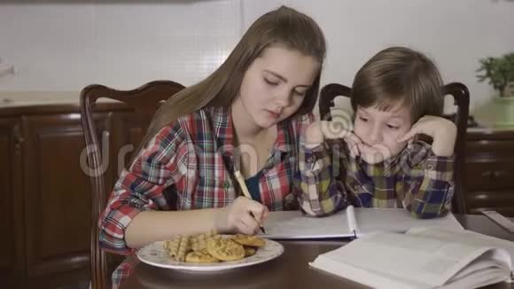 一位姐姐和弟弟学习功课的肖像一个女孩和一个小男孩做家庭作业视频的预览图