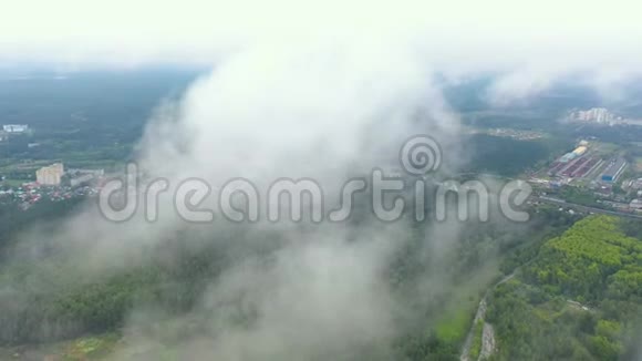 鸟瞰薄雾般的森林在大都市郊区的云层中飞翔下面是村庄的森林视频的预览图