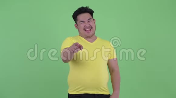 快乐的年轻超重亚洲男人笑着指着镜头视频的预览图