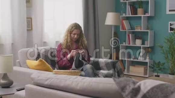 坐在沙发上在家庭作坊编织的幸福女人的恐慌视频的预览图