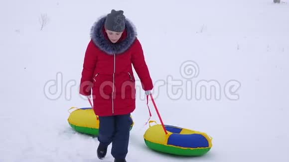 少女手持两个雪碟爬上高高的雪山圣诞节假期视频的预览图