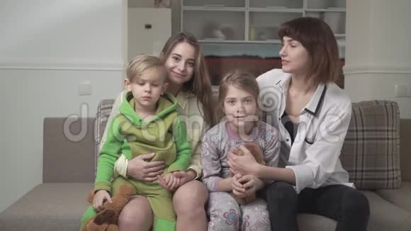 开朗幸福的一家四口人一起坐在沙发上家庭假日视频的预览图