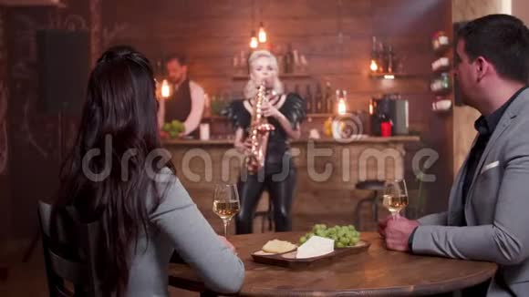 一对年轻夫妇在餐厅享受萨克斯管现场表演视频的预览图
