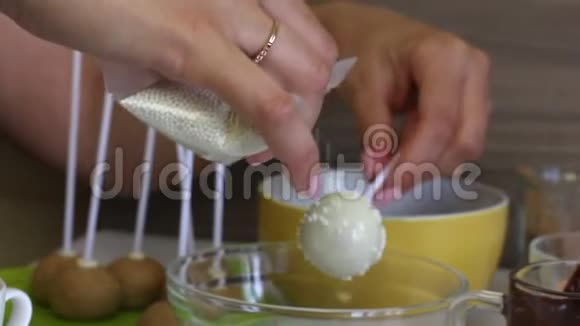 一个女人把白色的糖霜放在蛋糕上上面覆盖着白色巧克力用于均匀分布球上的敷料视频的预览图