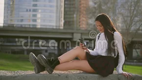 日本十几岁的女孩放学后在草地上打智能手机视频的预览图