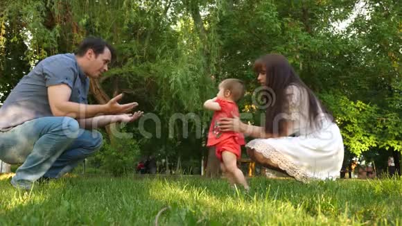 快乐宝贝在公园里和父母玩快乐的爸爸妈妈和他们的女儿在公园散步家庭价值观视频的预览图