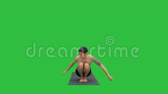 年轻男子蹲与扭转和弯曲瑜伽在绿色屏幕铬键视频的预览图