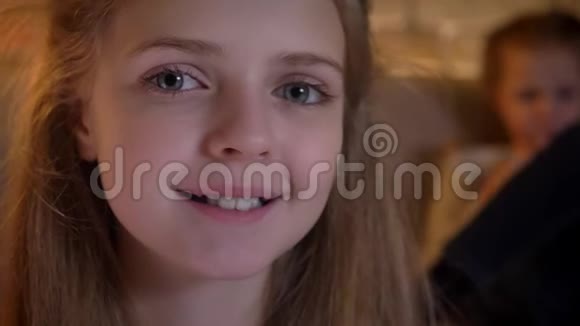 一张美丽的白种人女孩的特写照片她和她的姐妹在镜头中微笑地观看视频的预览图