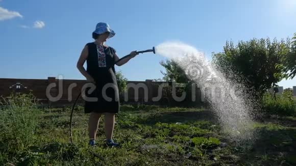 喜气洋洋的女人在阳光明媚的日子里缓慢地在花园里洗澡视频的预览图