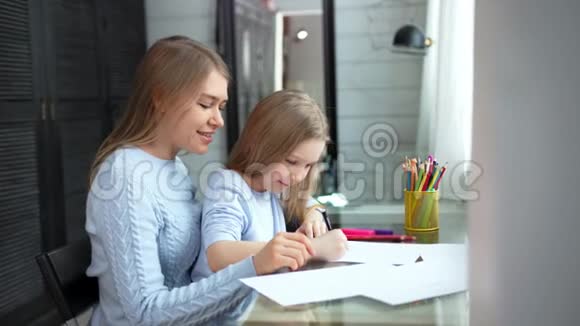 快乐的母女用彩色铅笔在纸上画画视频的预览图