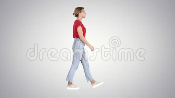 穿红色t恤牛仔裤和运动鞋的女人在渐变背景下行走视频的预览图