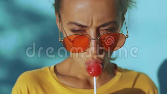 一个皮肤黝黑情绪激动的年轻女子脸上贴着红色大棒棒糖戴着红色眼镜的开朗女人视频的预览图