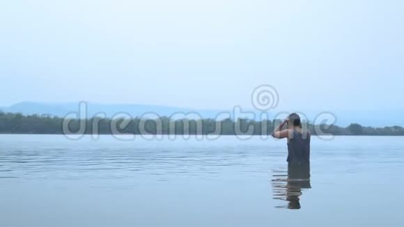 漂亮的亚洲人站在大湖边游泳使自己精神振奋视频的预览图
