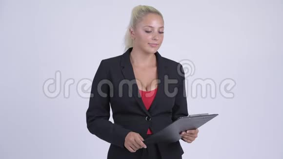 年轻快乐的金发女商人一边看剪贴板一边说话视频的预览图