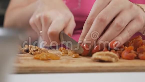 一位年轻的家庭主妇用一把刀在切割板上切割干果葡萄干健康饮食观念视频的预览图