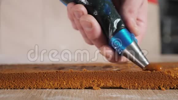 糖果厨师正把糕点袋中的焦糖馅放在海绵蛋糕上视频的预览图
