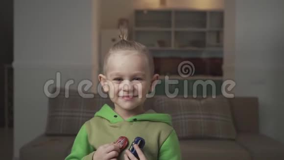一个小有趣的微笑男孩的肖像有一个时髦的发型摆着玩具车视频的预览图
