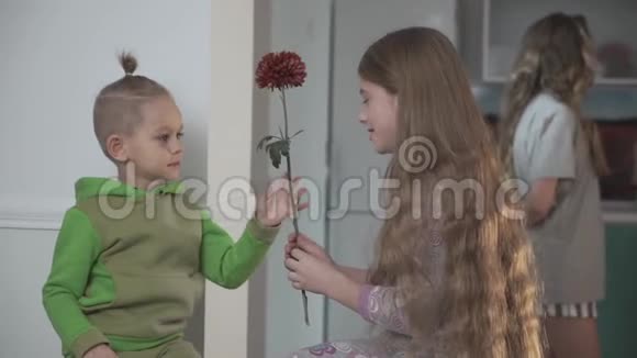 穿绿色睡衣的小男孩把花送给了姐姐大女孩的背景是把花送给了姐姐视频的预览图