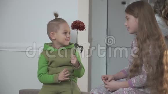 穿绿色睡衣的小男孩给他妹妹送花家庭关系视频的预览图