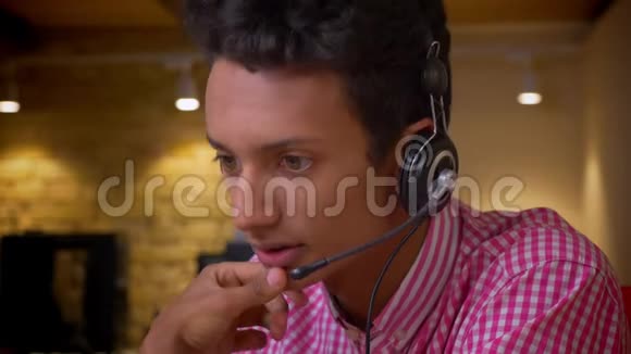 印度年轻员工在工作场所的办公室里使用笔记本电脑打电话的耳机特写镜头视频的预览图