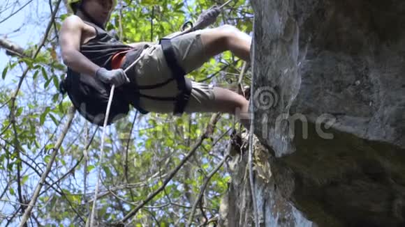 漂亮的亚洲男人从丛林的悬崖上爬出来非常危险视频的预览图
