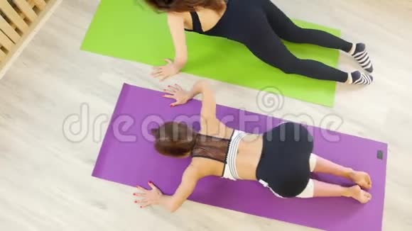 年轻女性在瑜伽垫上的工作室里做瑜伽脊柱放松练习视频的预览图