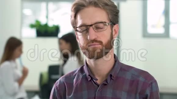 一个戴眼镜穿着休闲格子衬衫留胡子的人站在大厅的办公中心的画像视频的预览图