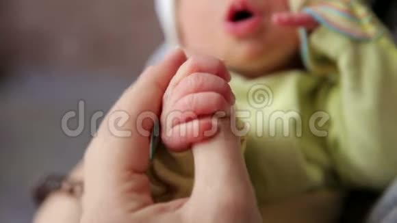 母亲抱着新生手的特写镜头宝宝抓着妈妈的手指视频的预览图