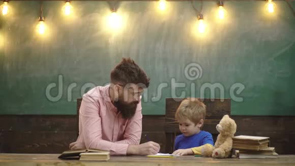 带着时髦胡子和胡须的老师和小孩子在复印本上写信可爱的男孩用视频的预览图
