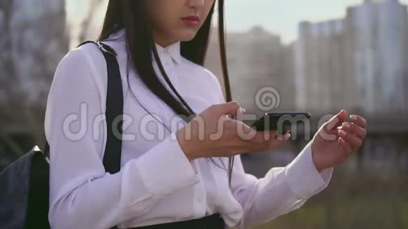 在看手机的亚裔女生有书包触摸头发和打字视频的预览图