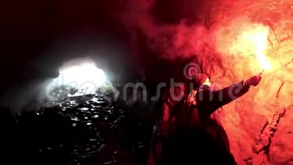 孤独的男人带着红色的燃烧信号在黑暗的洞穴里寻找洞旅游的概念库存录像男性视频的预览图