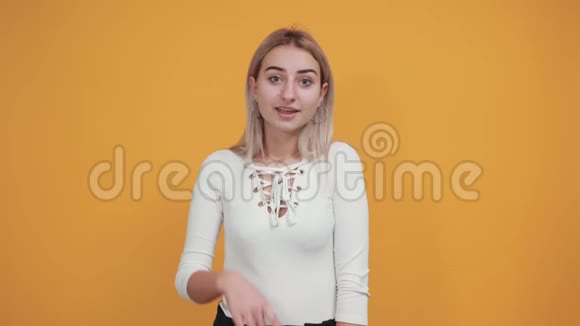 穿着白色衬衫的漂亮年轻女子在橙色的墙上隔绝空气视频的预览图