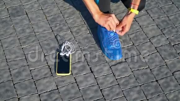 女跑步者用智能手表和智能手机准备跑步鞋的特写视频的预览图