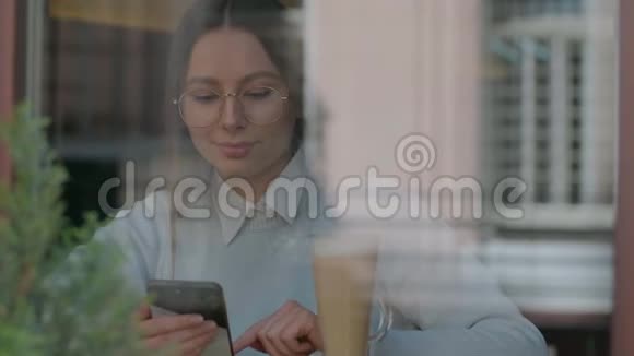 漂亮的女人在智能手机上使用应用程序在咖啡馆里聊天视频的预览图
