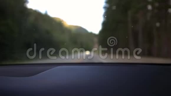 一个模糊的视野从一辆车的内部的山林公路与汽车冲在前景高清视频的预览图