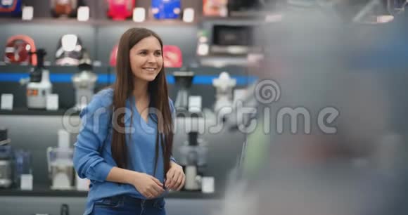 年轻漂亮性感的黑发女郎在电器商店为厨房选择了搅拌机视频的预览图