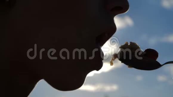 年轻女人的嘴正拿着一个汤匙和草莓放在户外视频的预览图