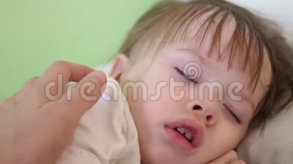 妈妈用手摸着小宝宝的额头检查小宝宝睡觉的温度视频的预览图