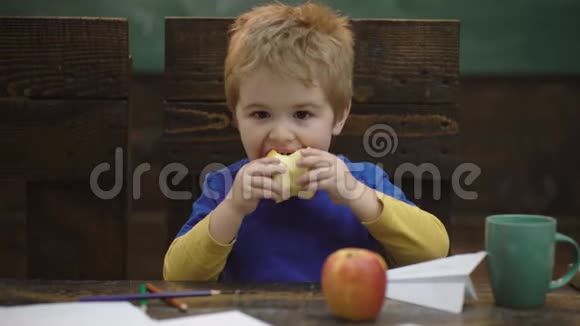 学校休息饥饿的孩子在教室里吃苹果小学生午休时吃苹果健康食品视频的预览图