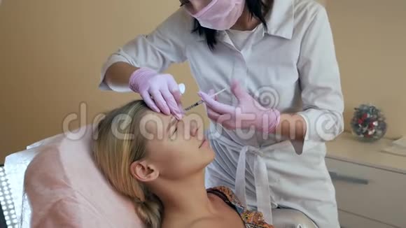 美容诊所美容师用手套在女性皮肤上进行面部老化注射女人做美容视频的预览图