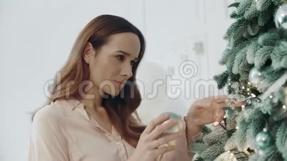 放松的女人在客厅装饰圣诞树视频的预览图