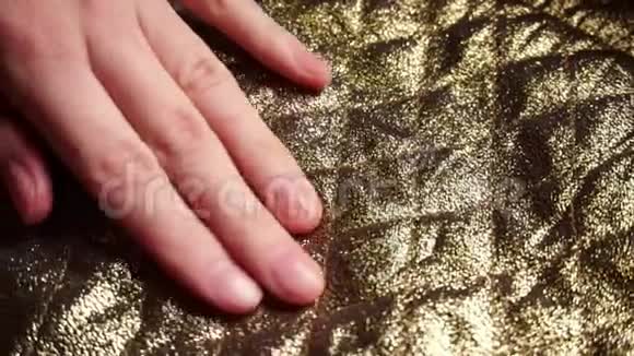 女人触摸一个光滑金色尼龙涤纶织物在一家纺织品商店视频的预览图