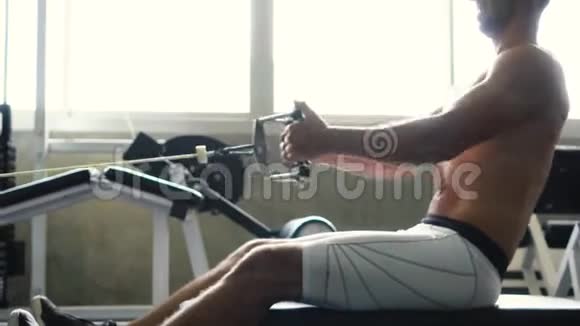 无衫肌肉男在健身房的机器上做坐索排运动视频的预览图